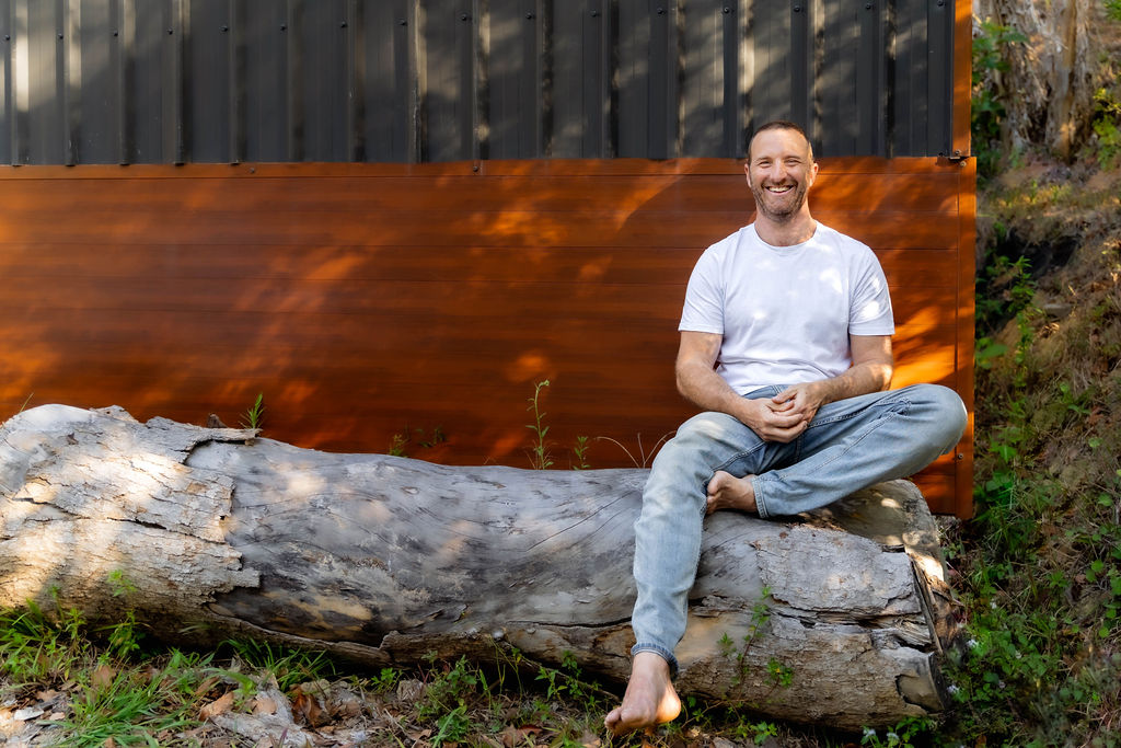 Rich laughing while sitting on a log